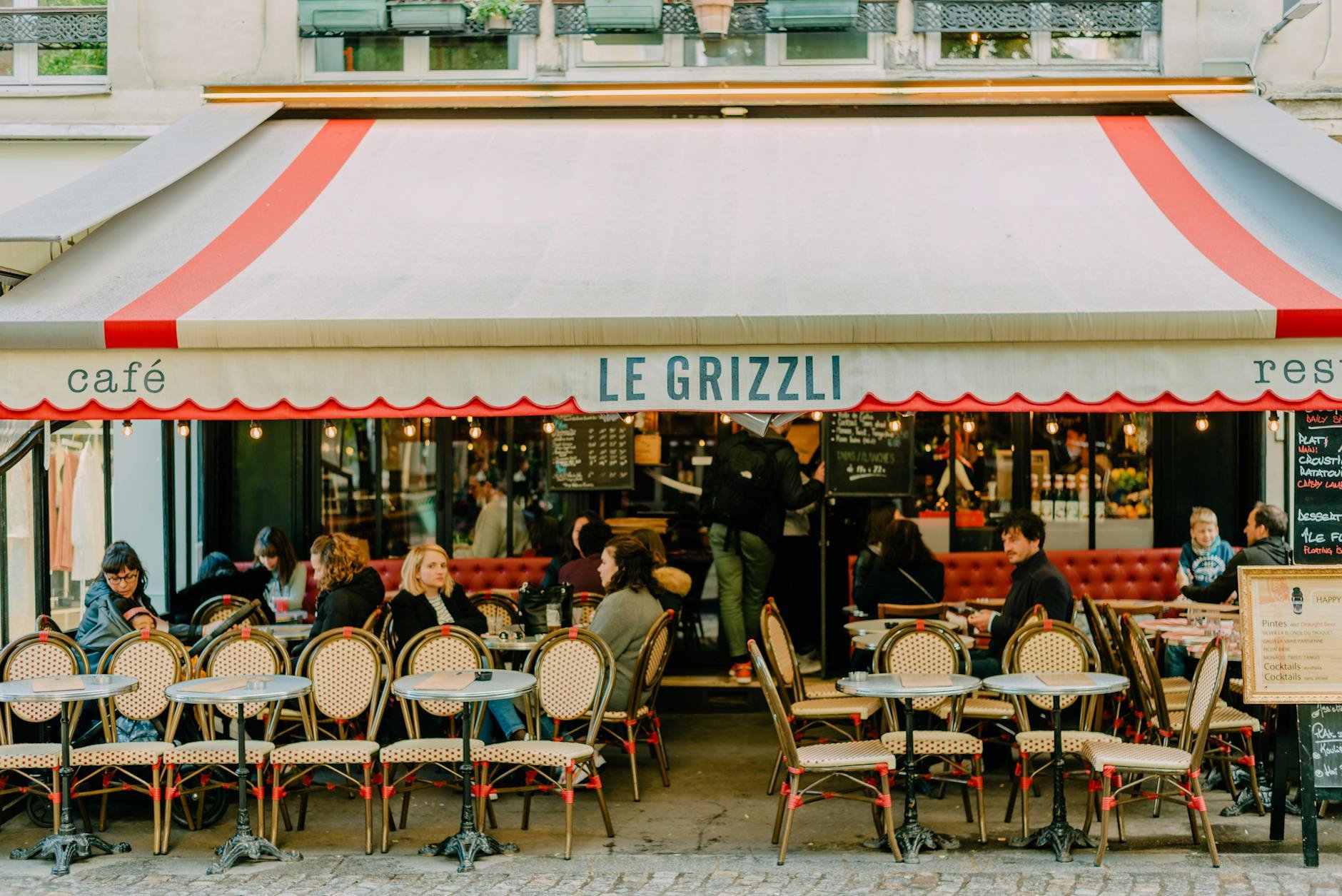 Cafe storefront with red-and-white awning and sidewalk seating