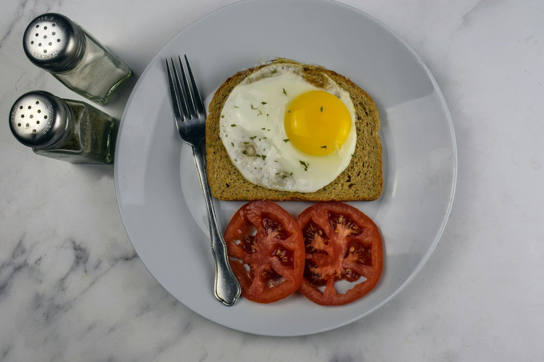 Breakfast plate with fried egg on sourdough toast and tomato slices