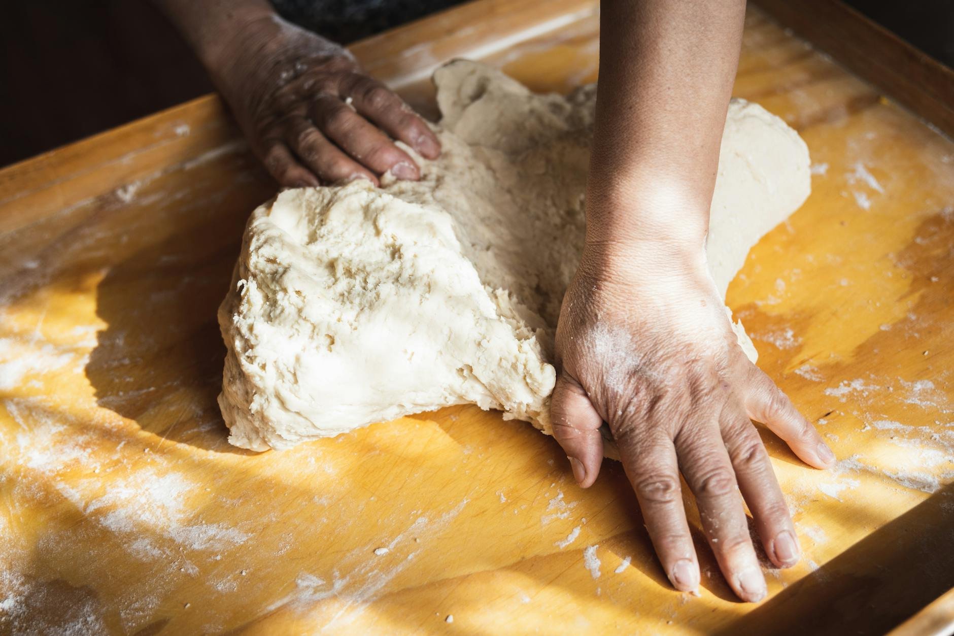 Pizzaiolo hands kneading dough on a floured surface