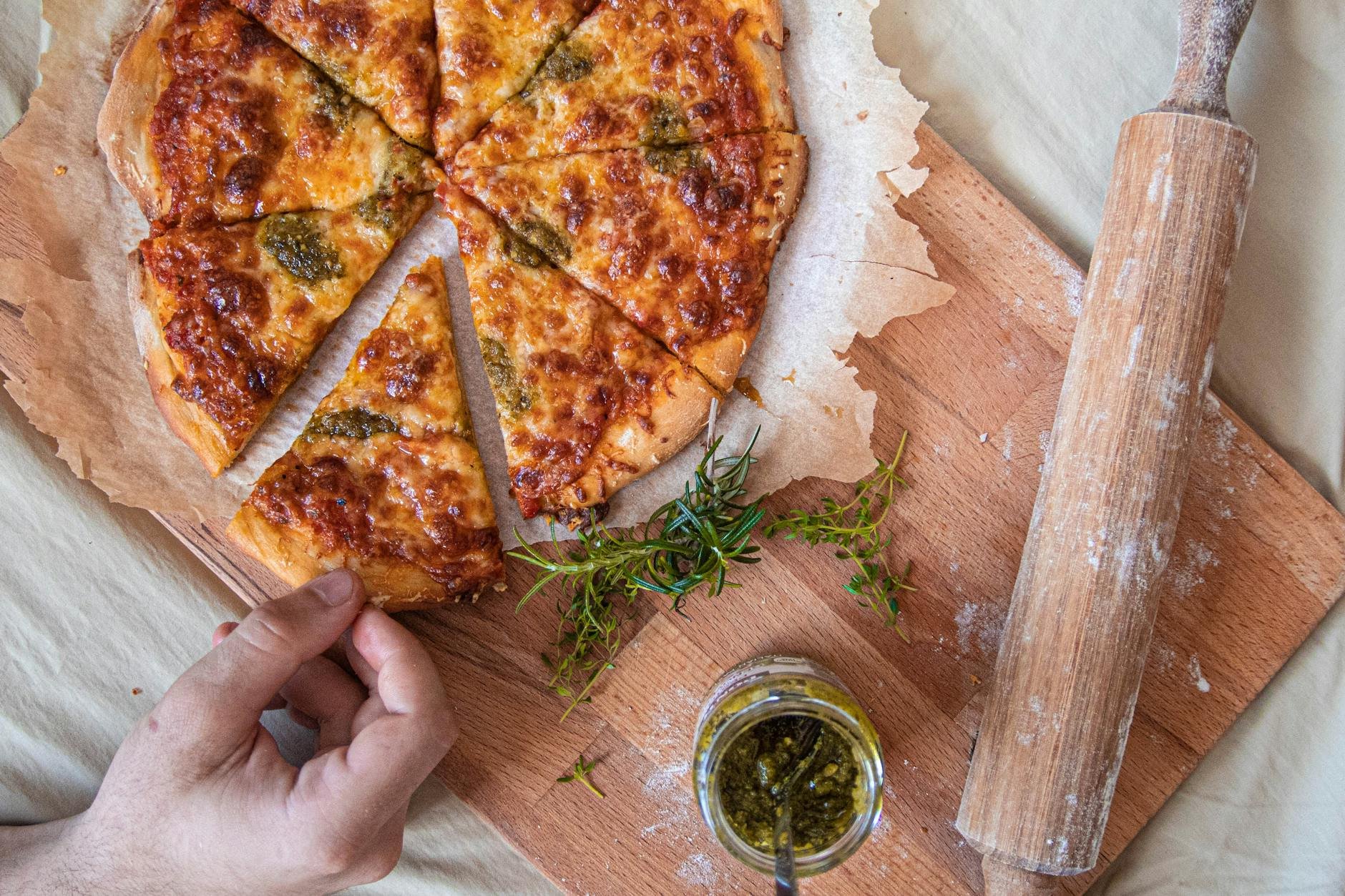 Rustic pizza on a wooden board with rolling pin and fresh basil